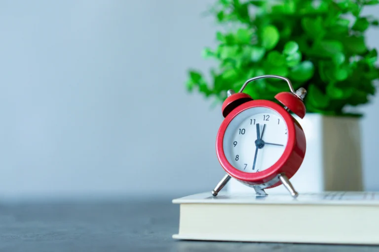 Small red desk clock symbolizing time control and productivity focus at the workspace