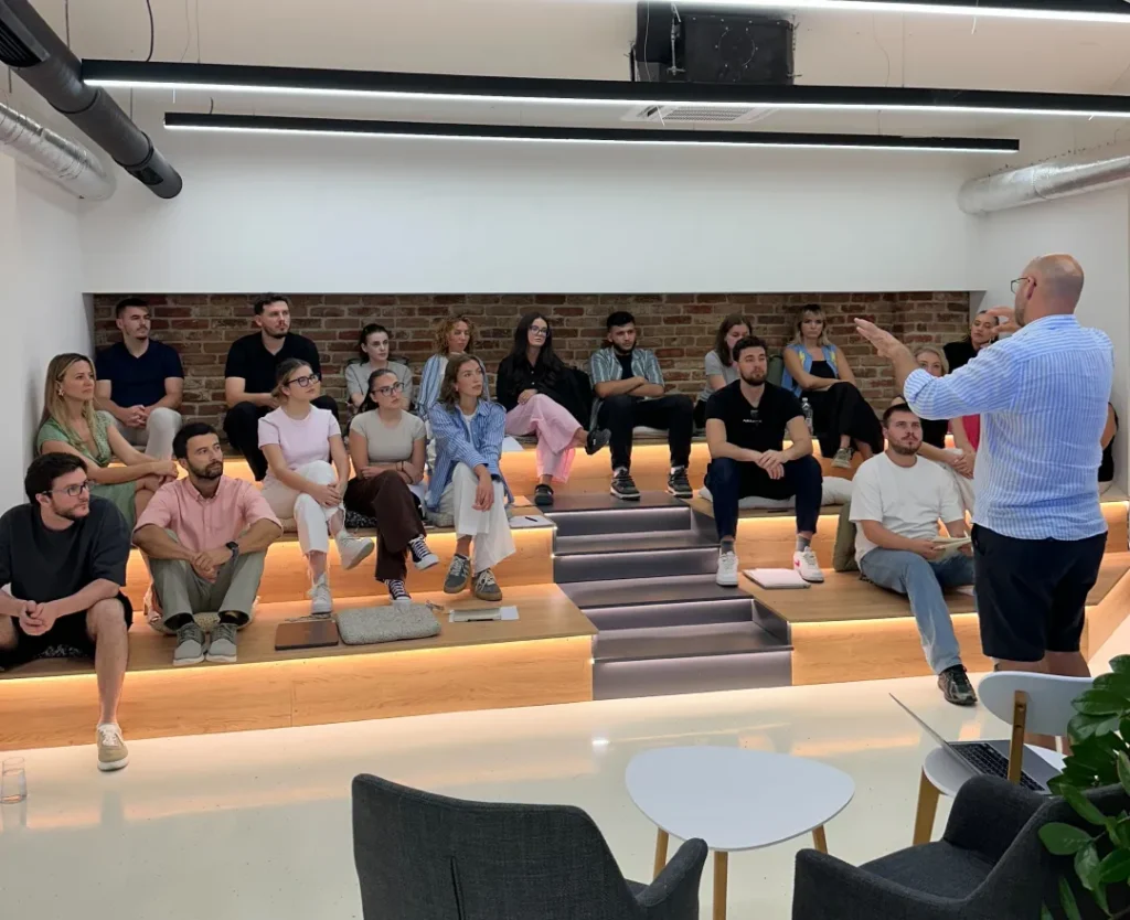 AnchorzUp team seated in amphitheatre listening to Naser Morina's speech on Small Steps